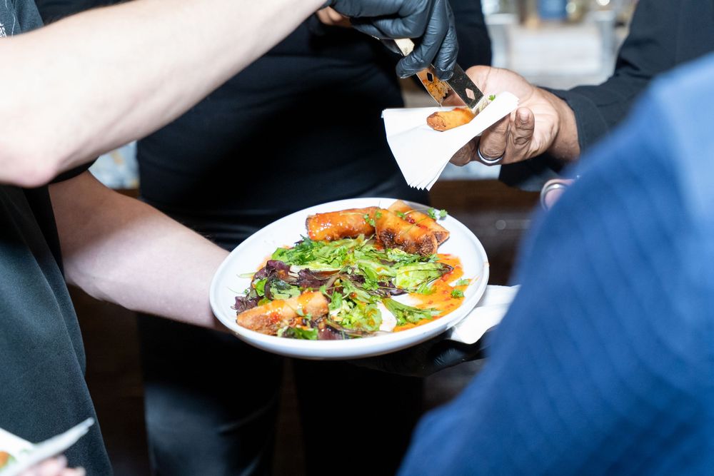 Close-up of a gourmet salad plate with shrimp and greens being served at a catered event.