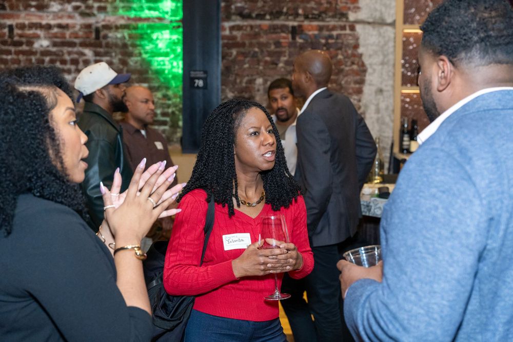 Women networking at a professional event, engaged in lively conversation while holding drinks.