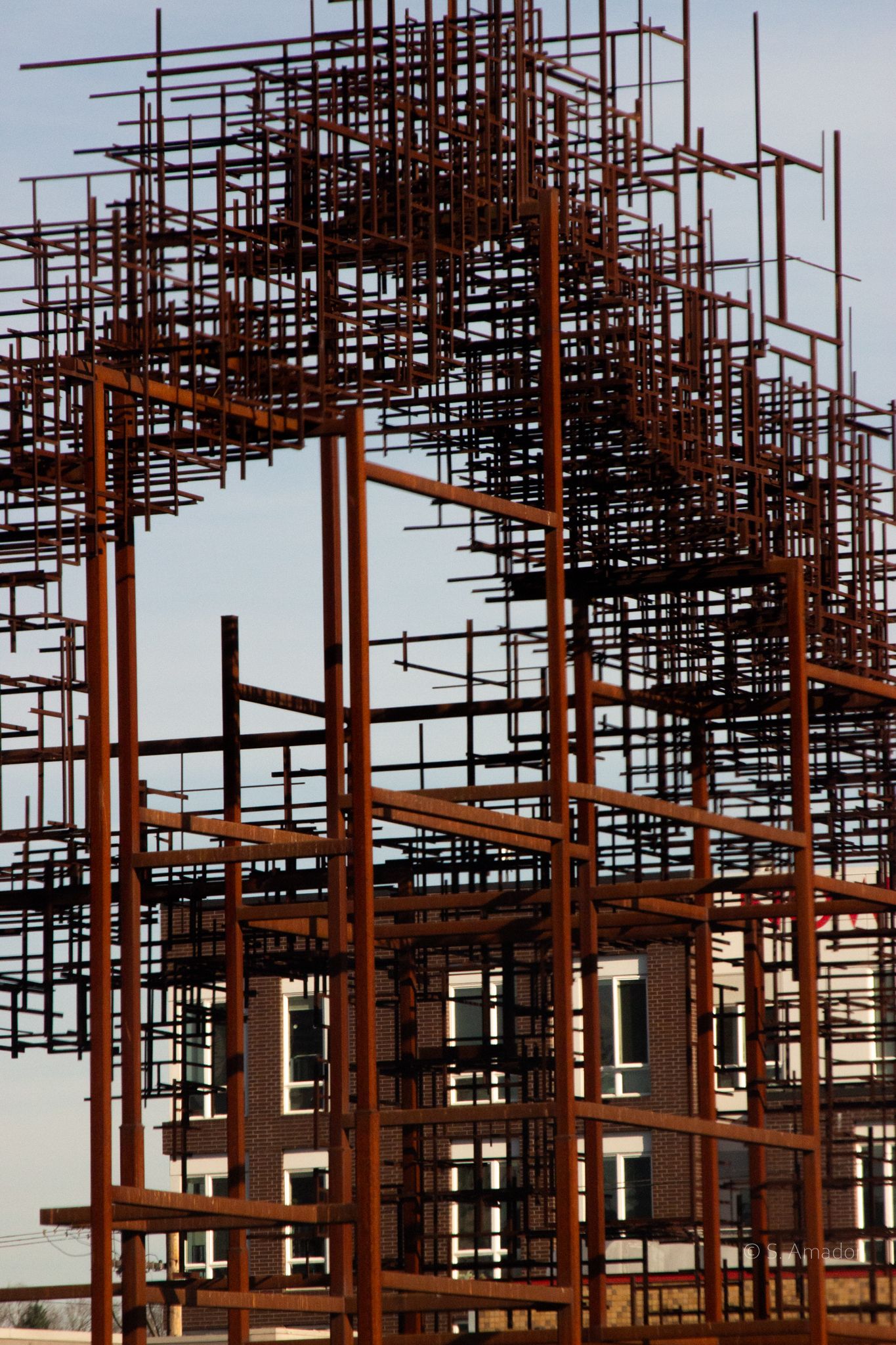 Rusty steel rebar scaffolding framework at a construction site with a building visible in the background.