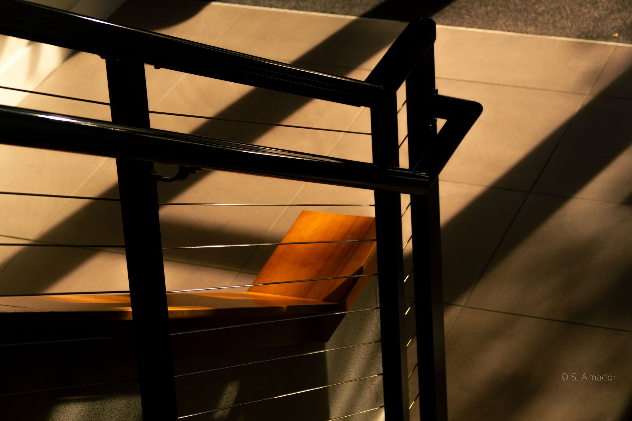 Abstract golden light and shadows cast through metal railings on warm-toned surfaces.