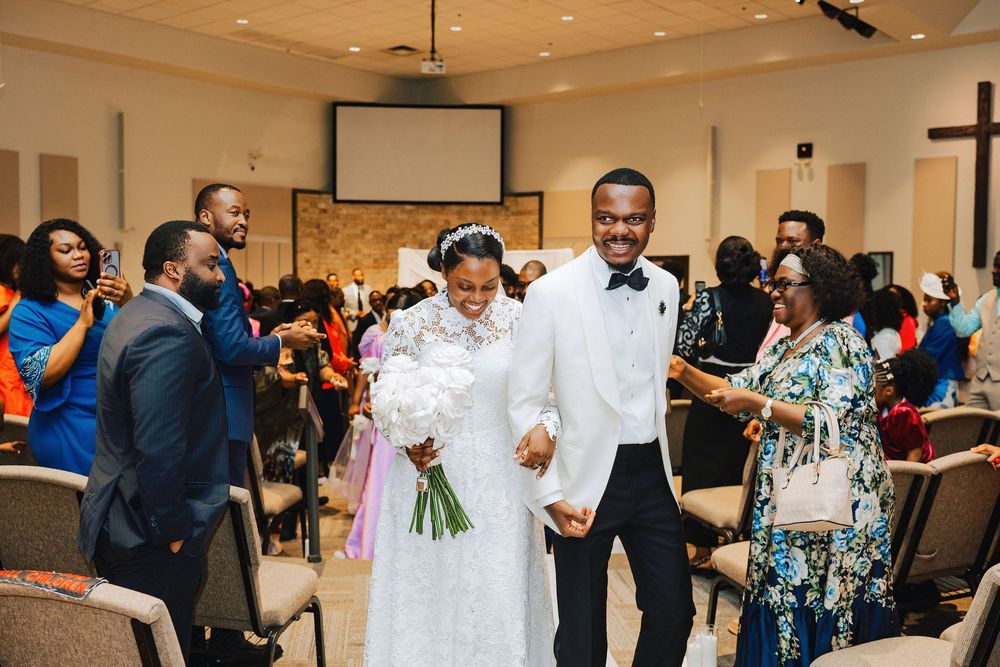 Joyful newlyweds walk down the aisle at their wedding ceremony as guests celebrate around them.