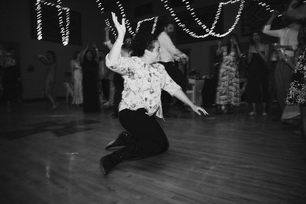 Black and white photo of a guest dancing energetically on the wedding reception dance floor.