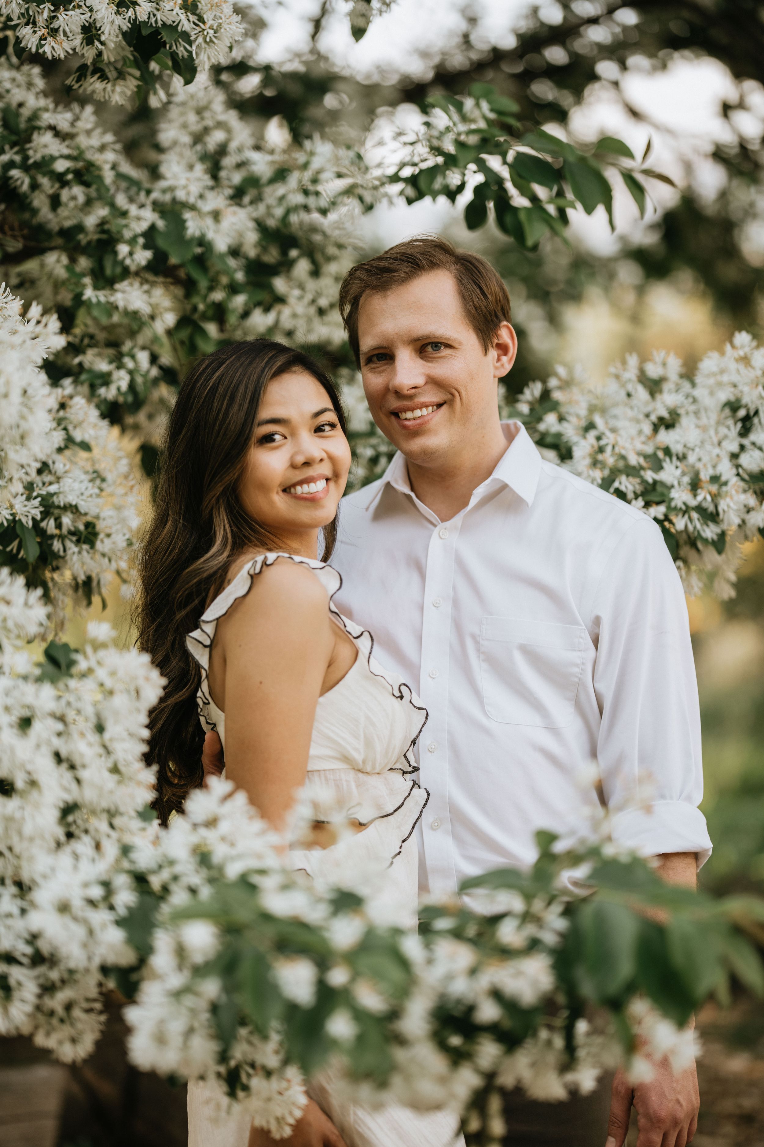 Mariel and Jeff smiling among white blossoms at the Los Angeles County Arboretum.