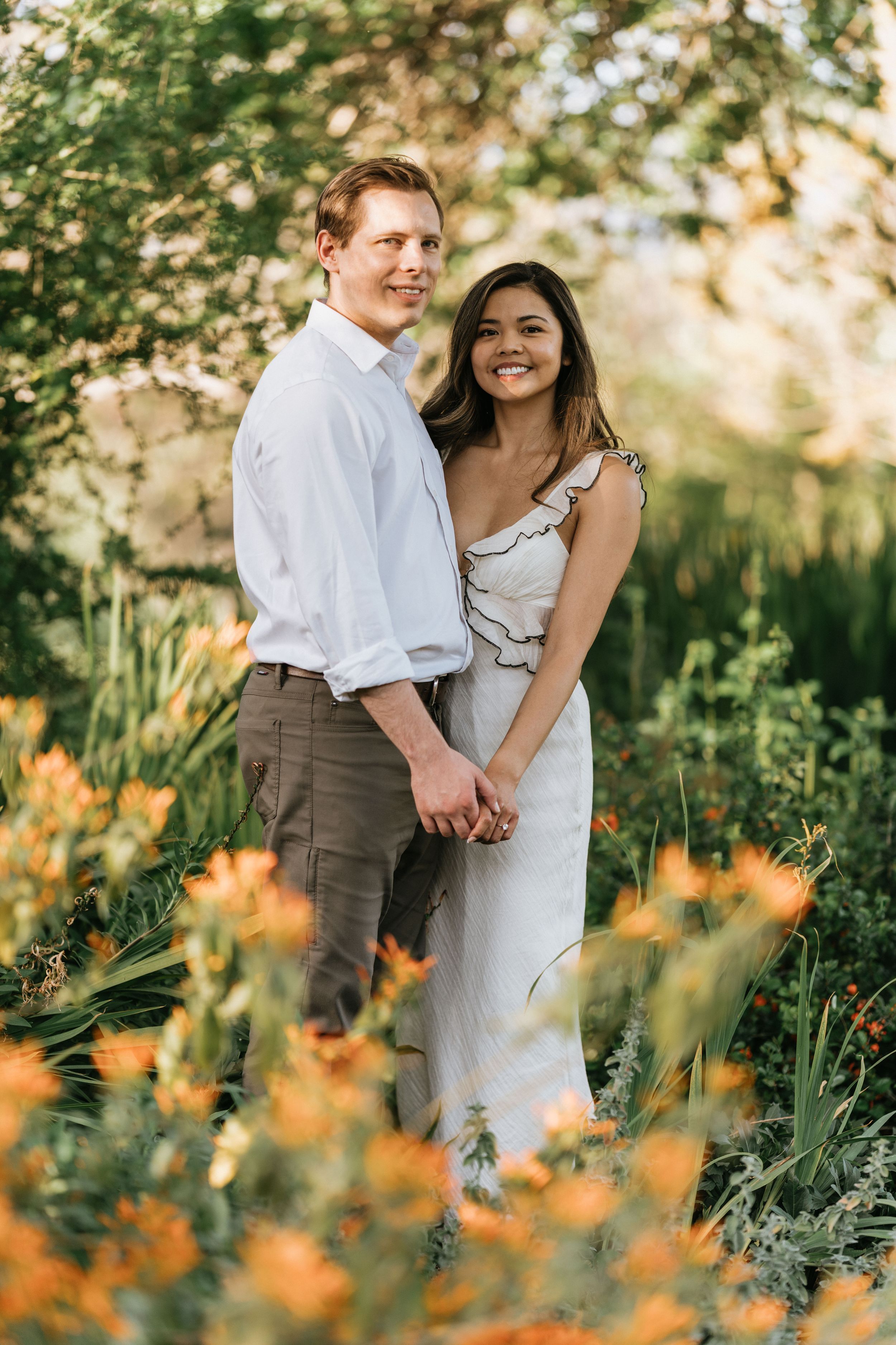 Mariel and Jeff holding hands among colorful spring flowers at the Arboretum.