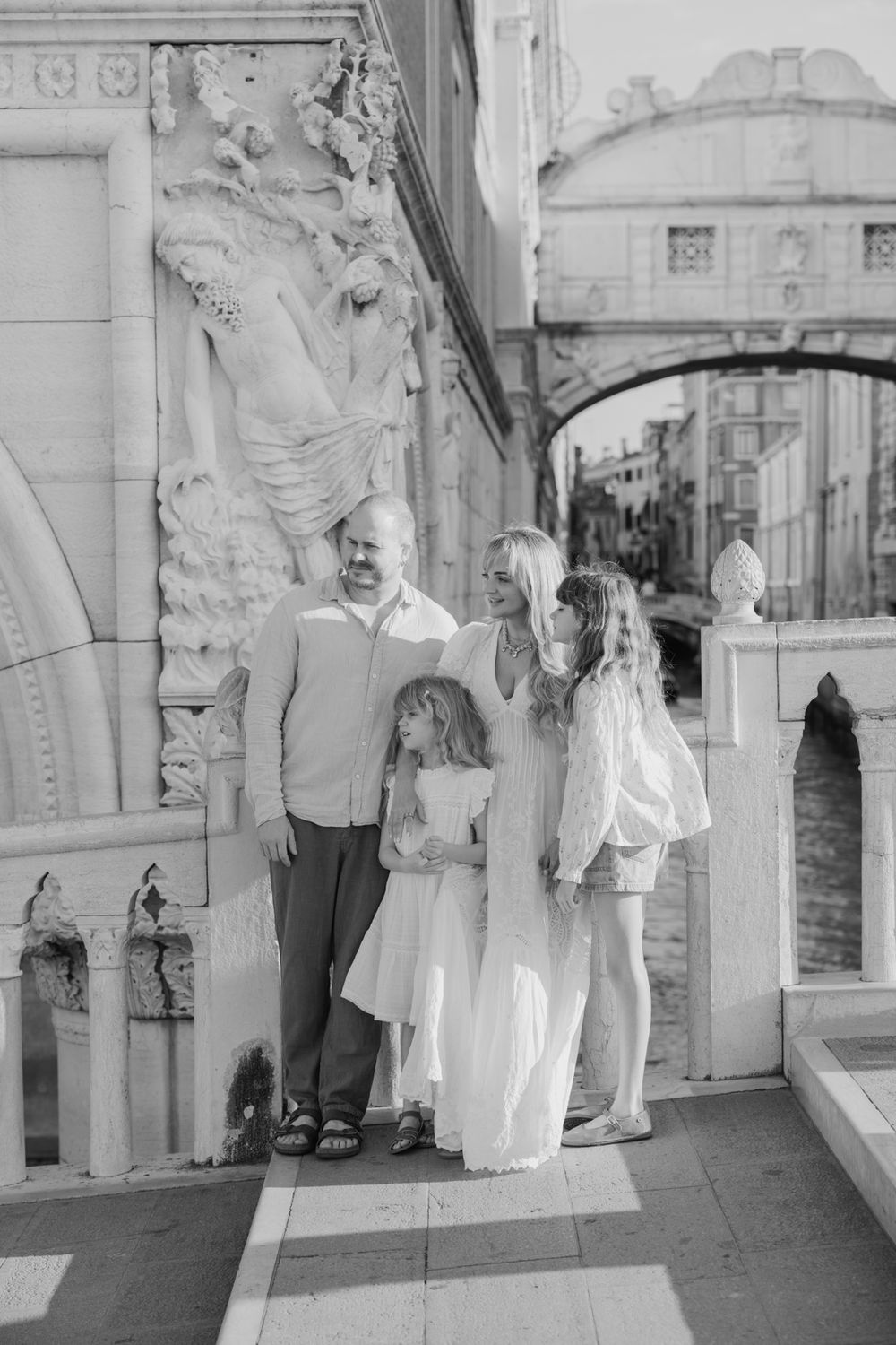 Black and white family portrait near Bridge of Sighs ornate stonework in Venice, Italy.
