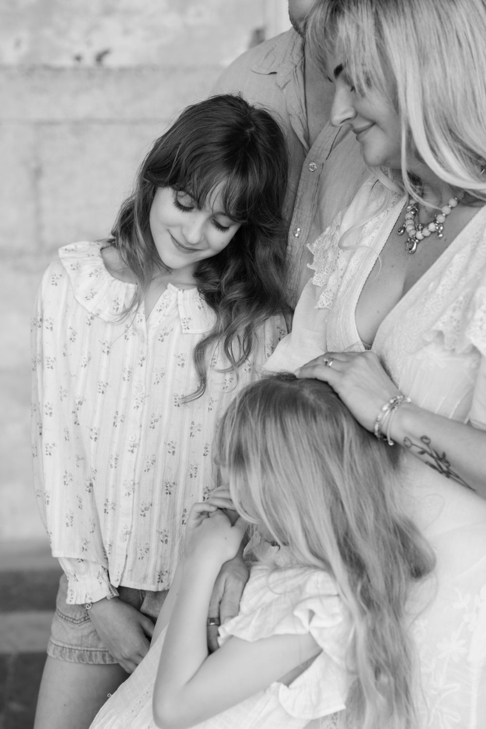 Black and white photo of a mother with two daughters sharing a tender family moment.