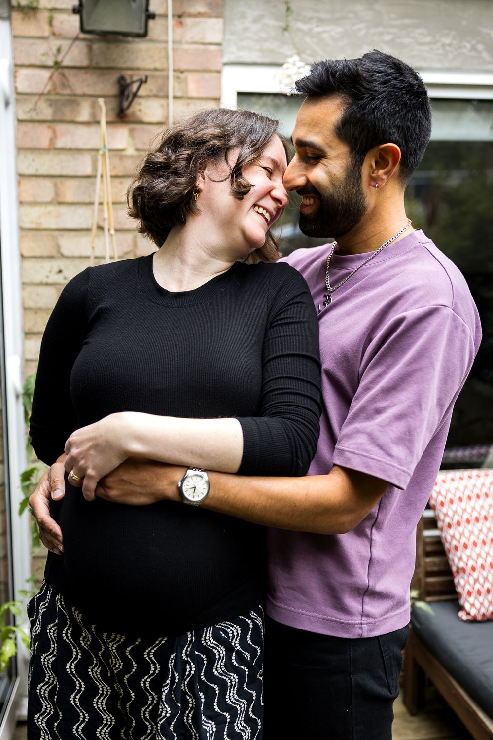 husband and wife embracing pregnant bump