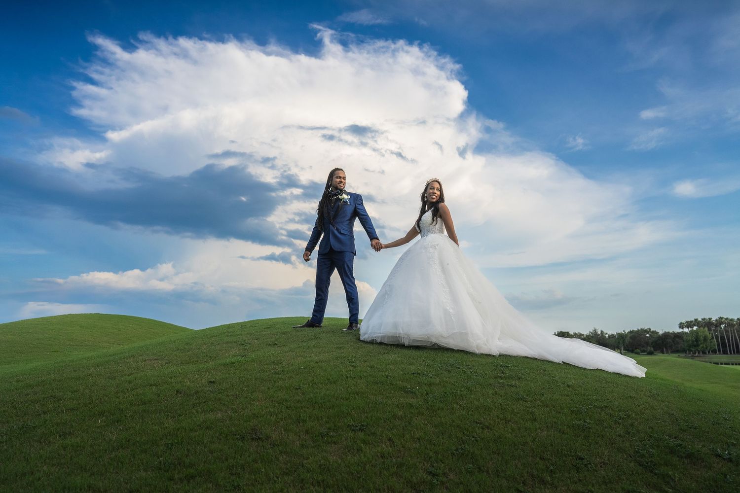Wedding couple portrait on green hill dramatic blue sky Orlando Florida Weddings by Ray