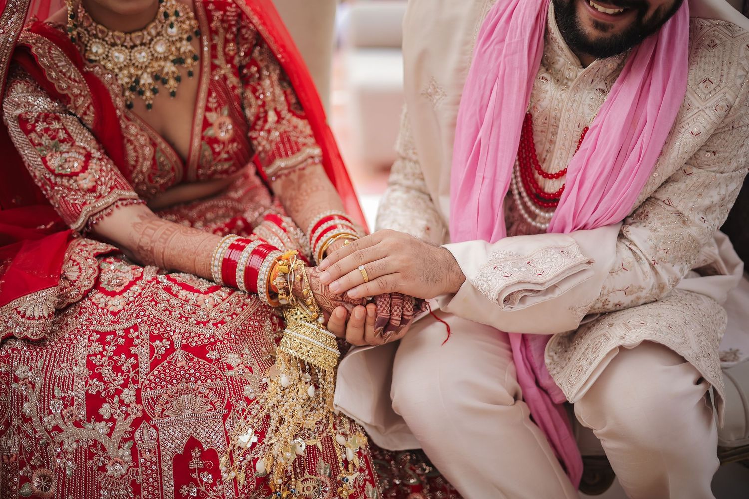 Indian bride and groom in traditional wedding attire holding hands during Hindu marriage ceremony.