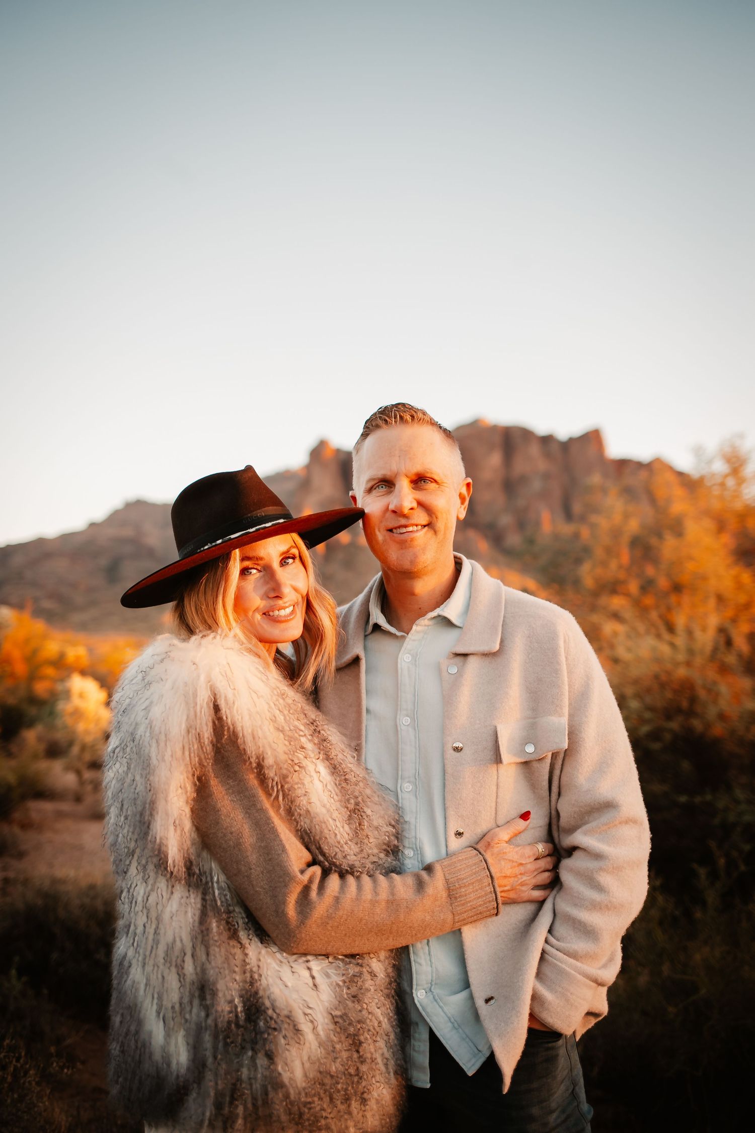 Mindee and Josh smiling together outdoors at golden hour in a desert landscape.