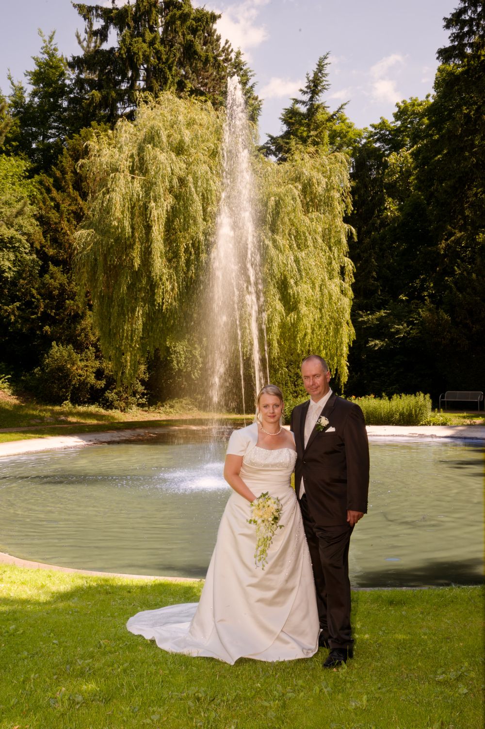 Brautpaar posiert vor dem großen Springbrunnen im Stadtpark Forchheim. Stimmungsvolle Hochzeitsfotografie in der Region.
