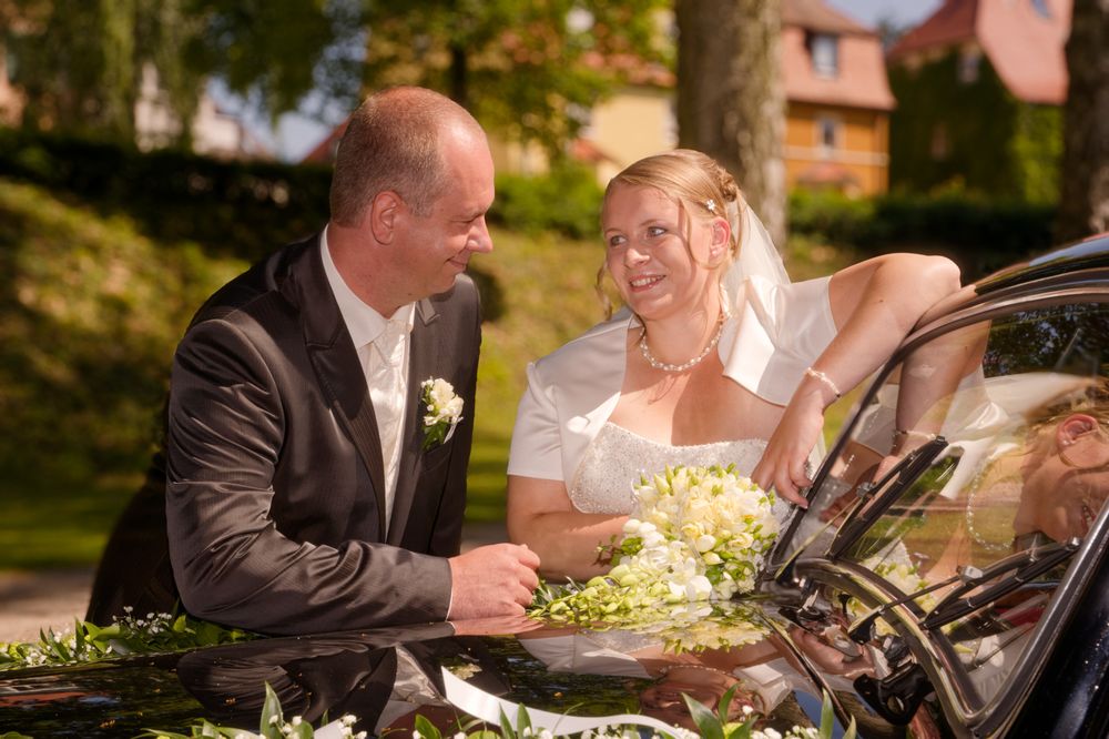 Brautpaar genießt einen intimen Moment an ihrem geschmückten Hochzeitsauto. Romantische Hochzeitsbilder aus Forchheim.