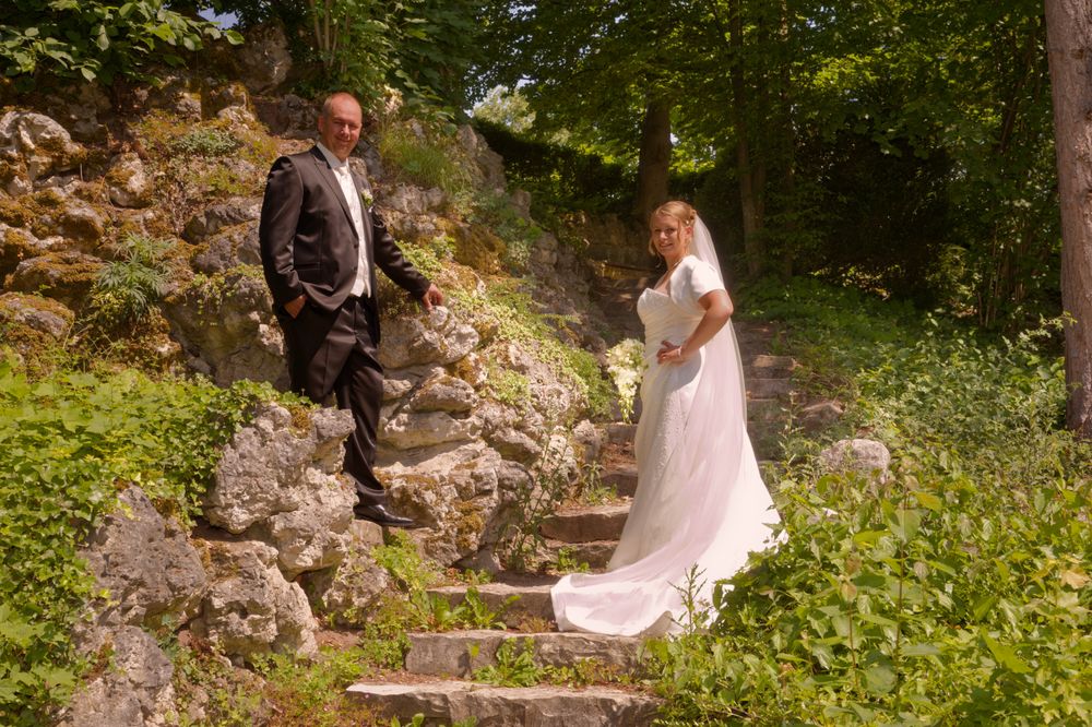 Brautpaar steht innig beieinander auf einer Steintreppe im Stadtpark Forchheim. Hochzeitsfotografin für natürliche Bilder.