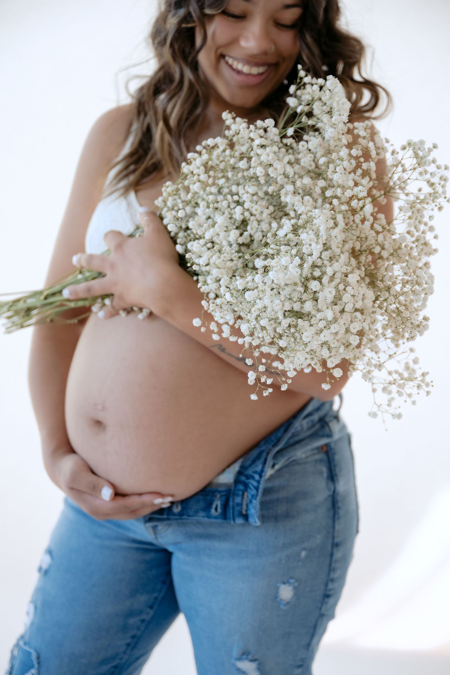 Maternity portrait of baby bump with baby's breath flowers during in studio pregnancy session in stillwater MN with Jagger Rose Photography