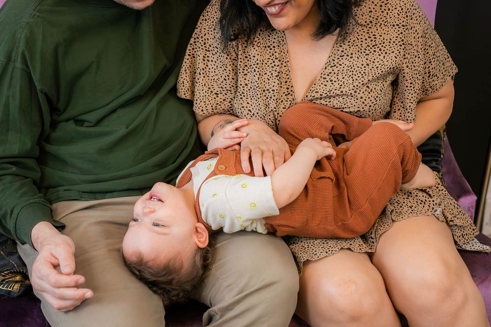 A small child lying comfortably across laps in casual family clothing.