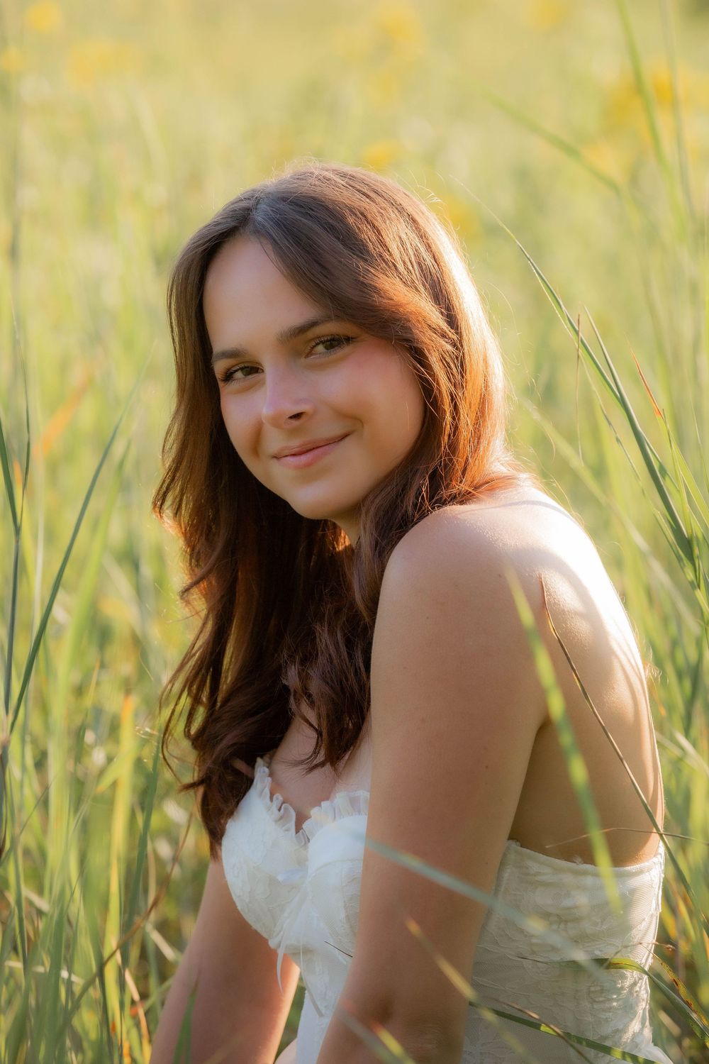 Warm sunset light illuminates a portrait in a serene meadow of tall grass on a summer evening.