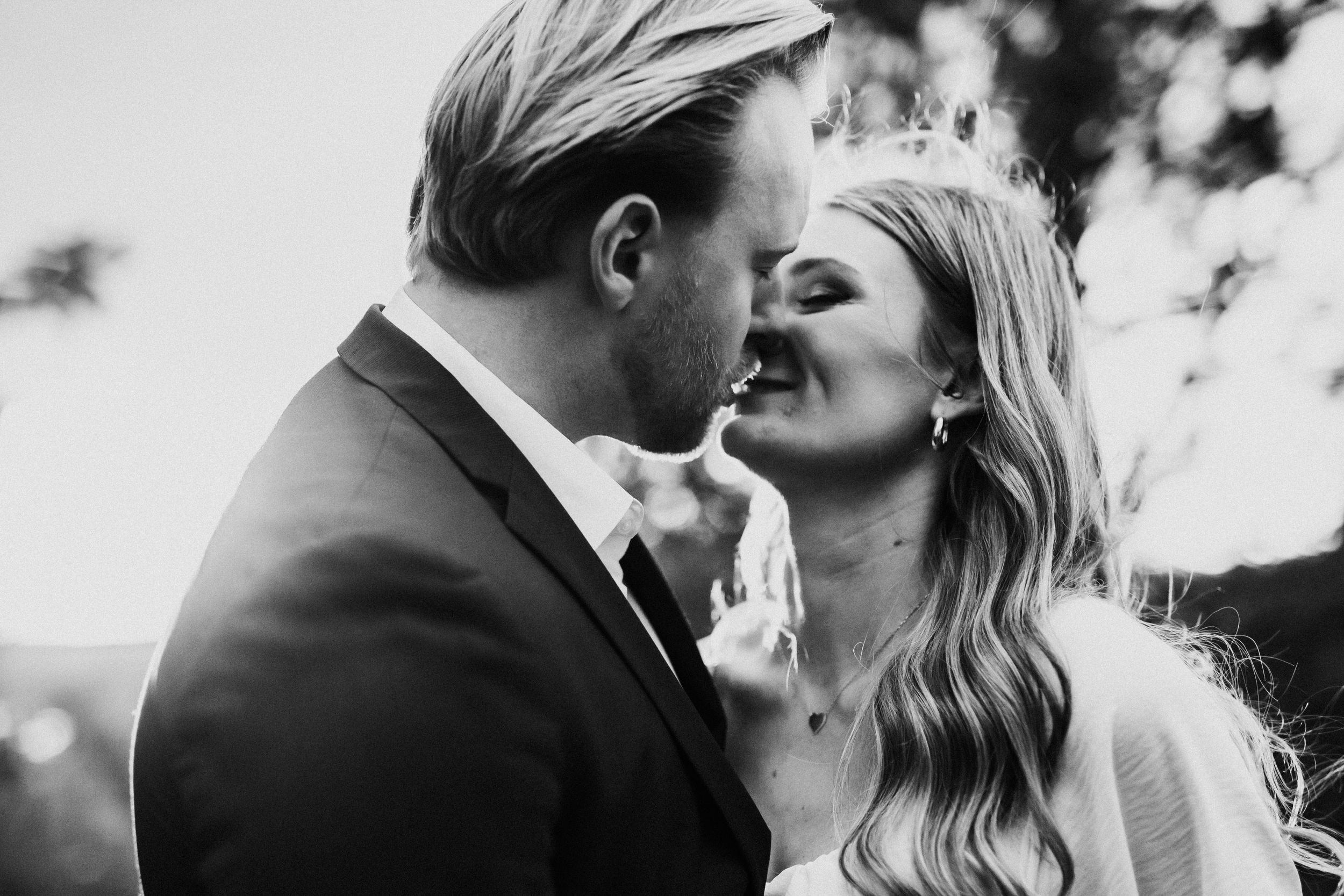 A romantic black and white close-up of a couple sharing an intimate moment outdoors.