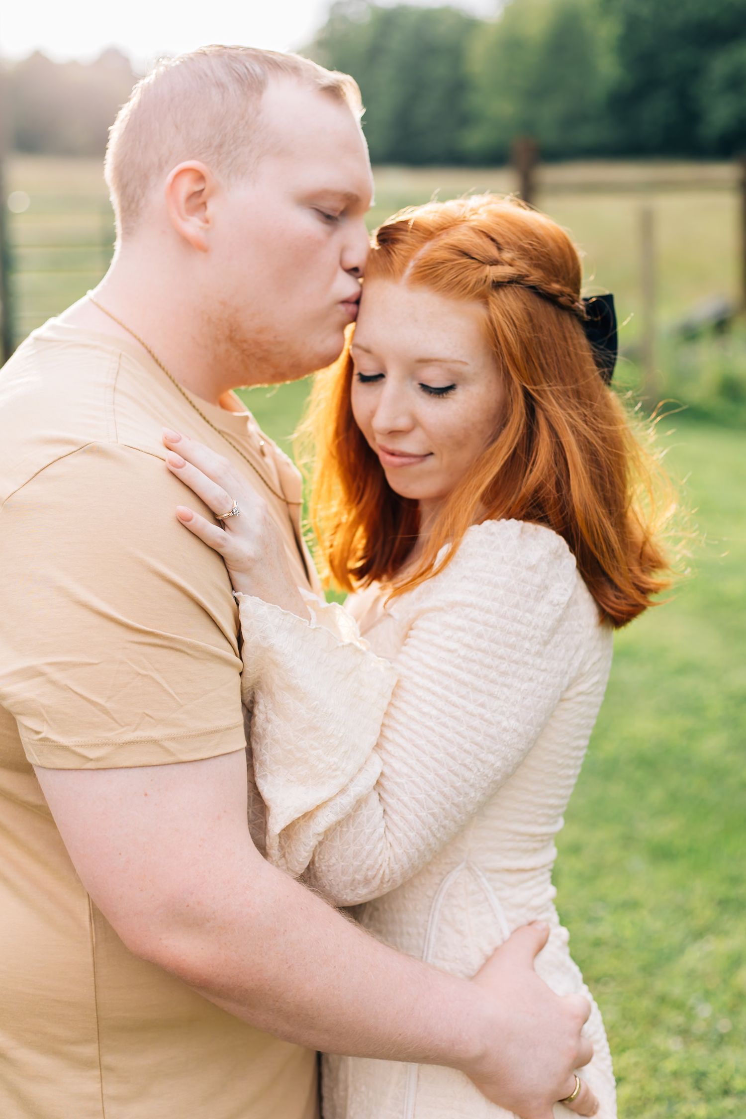 A couple in casual cream-colored attire shares tender moments during an engagement photoshoot.