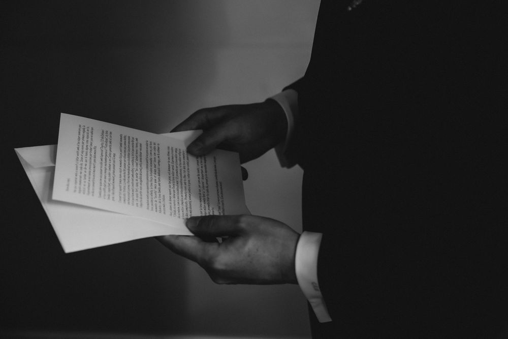 Professional hands holding business documents in dramatic black and white lighting against dark background.