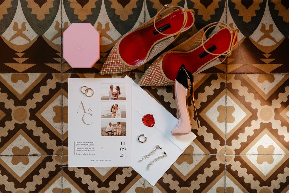 Wedding invitation suite with red and pink floral details laid out on a geometric patterned surface.