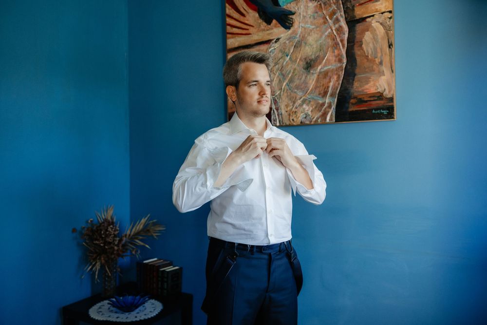 A series of photos showing someone adjusting a white collared shirt against a vibrant blue wall background.