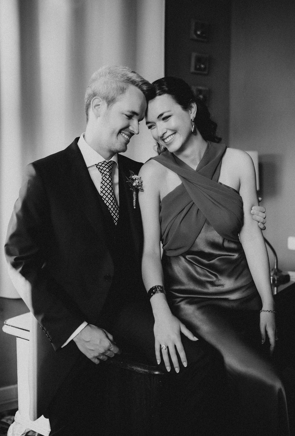 A romantic black and white portrait of a couple in formal attire sharing an intimate moment together.
