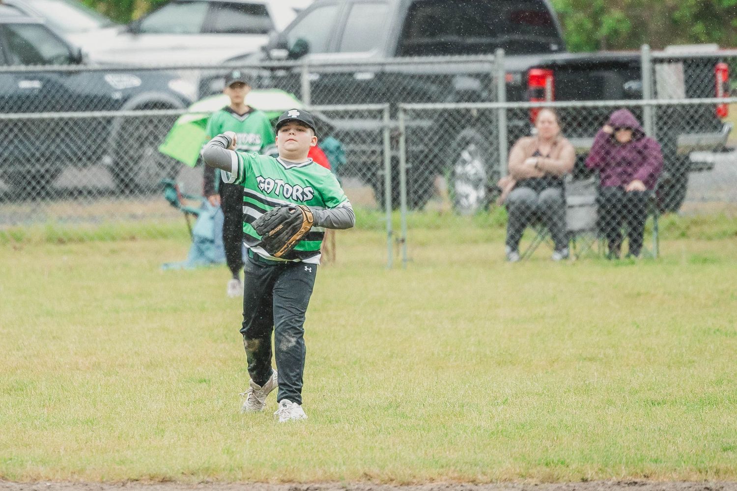 Young baseball player in green uniform running across a grass field during a game.