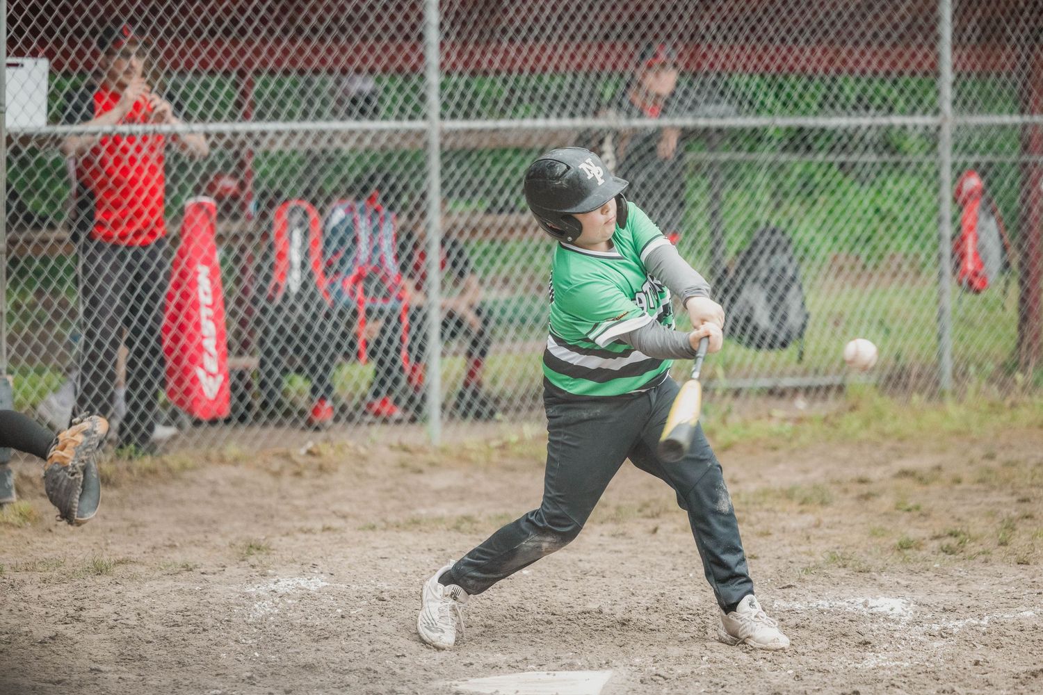 Baseball player in green uniform taking a swing at bat during a game.