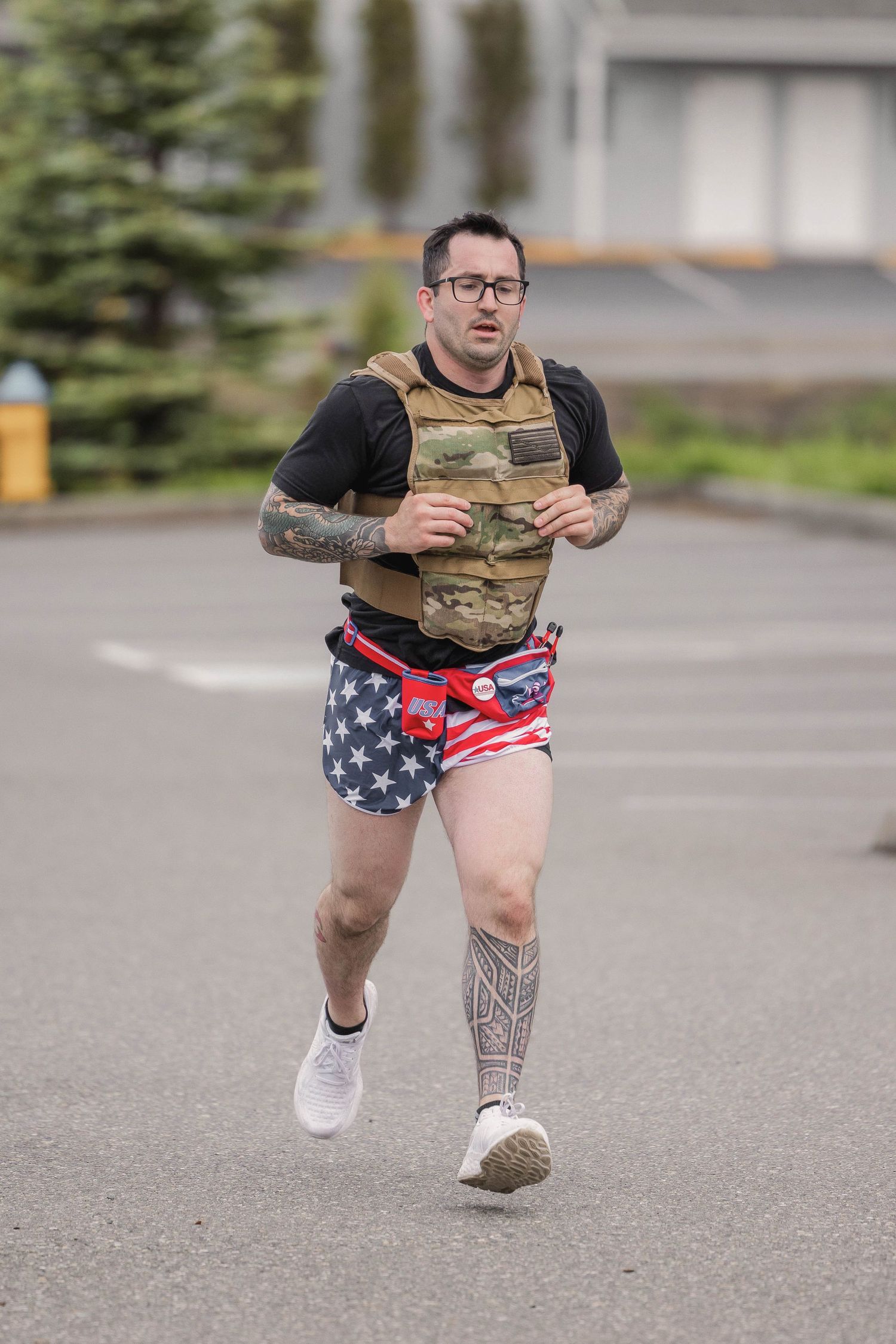 Runner wearing patriotic shorts and tactical vest exercising outdoors.