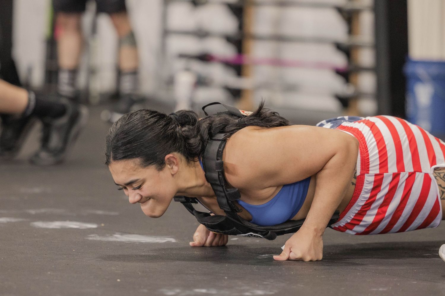 Athlete performing push-ups during an intense workout session in a CrossFit gym.
