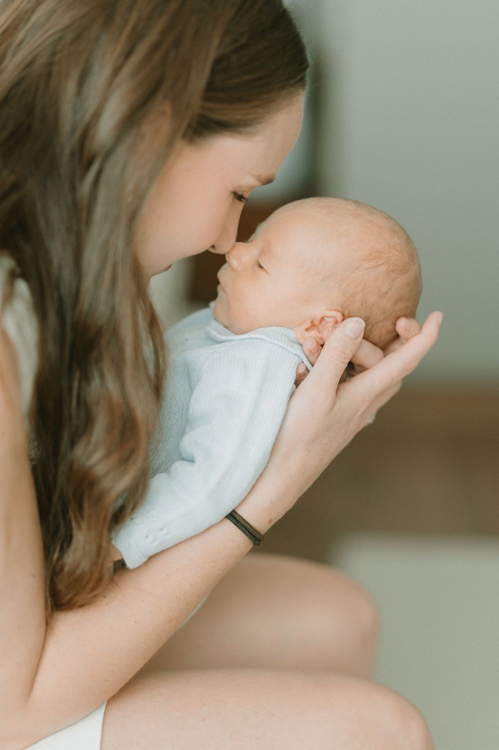 Intimate portrait of gentle moment with baby in light blue outfit.