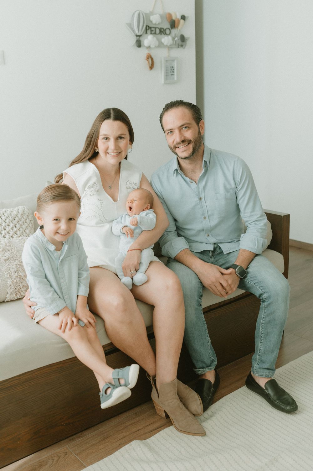 Happy family portrait on wooden bench in bright modern room.