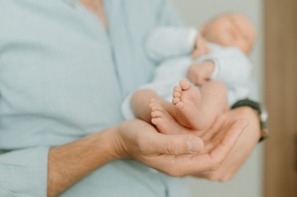 Close-up of tiny baby feet being gently cradled in adult hands.