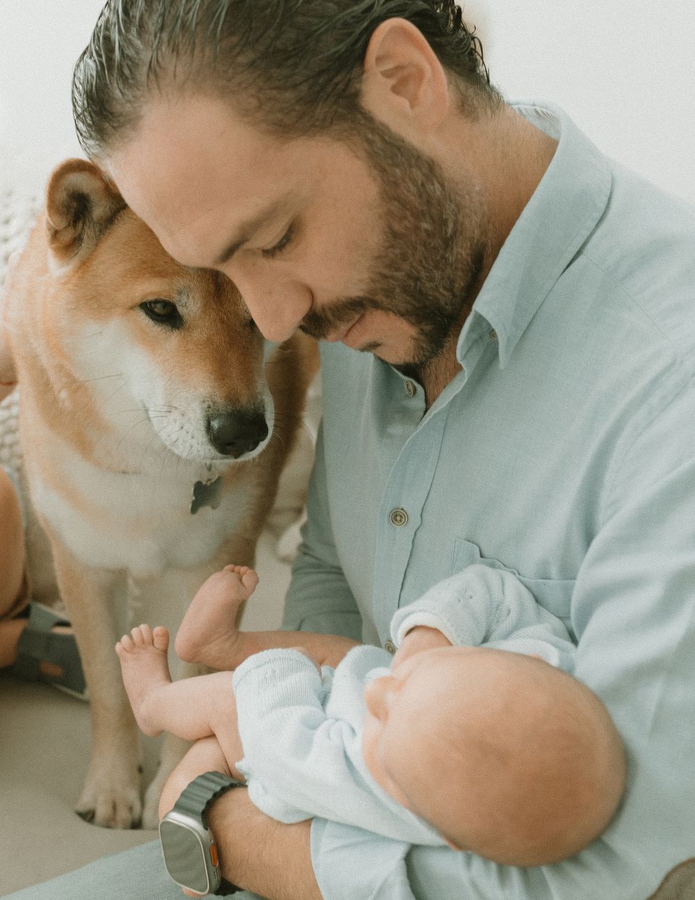 Sweet moment shared between Shiba Inu dog and baby in light blue outfit.