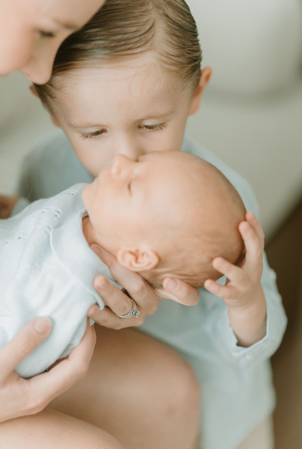 Tender moment of affection with baby wearing soft blue clothing.