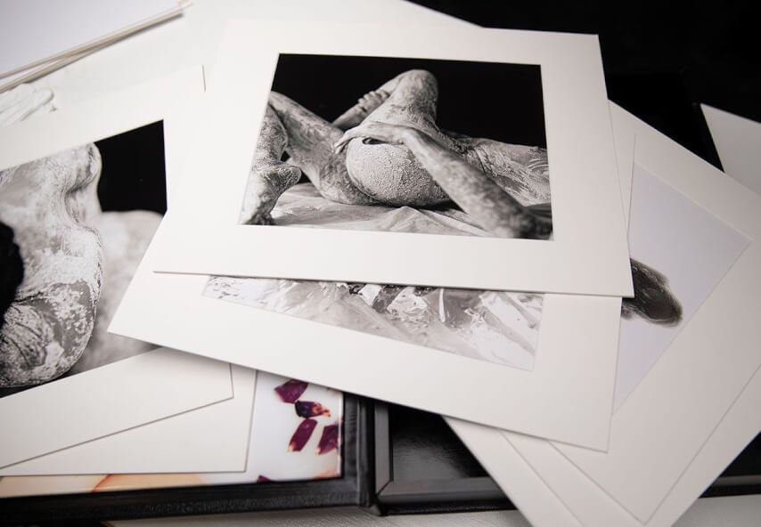 Collection of black and white fine art prints scattered on a white surface.