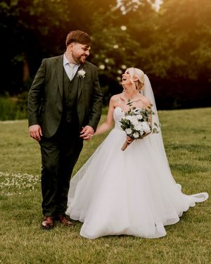 Wedding couple posing romantically on a grassy lawn during sunset.