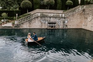 A romantic wedding boat ride on an ornate pool with classical stone architecture.
