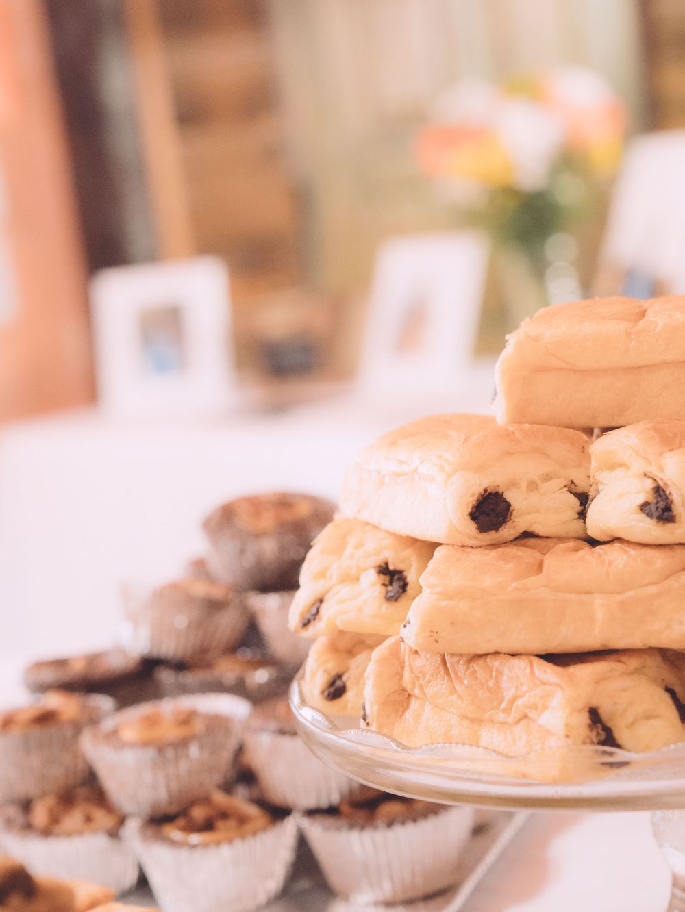 Stack of chocolate chip pastries on glass stand at catered event table.
