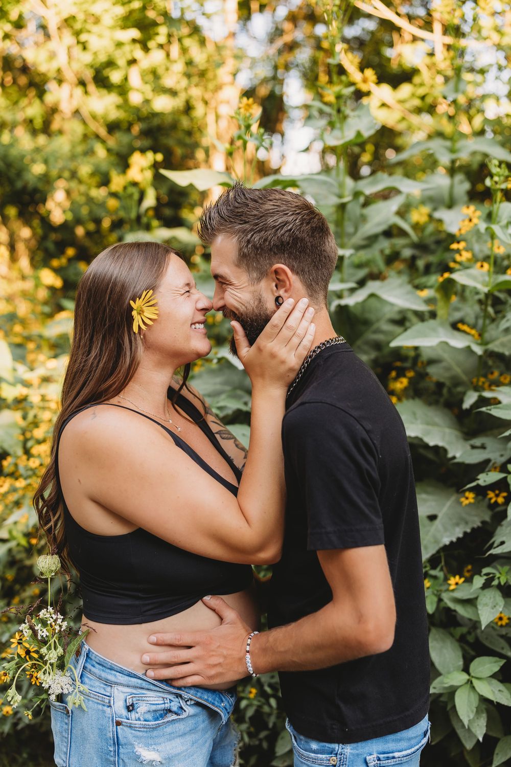 couple maternity sunflowers butterflies embrace rubbing noses black shirts and blue jeans