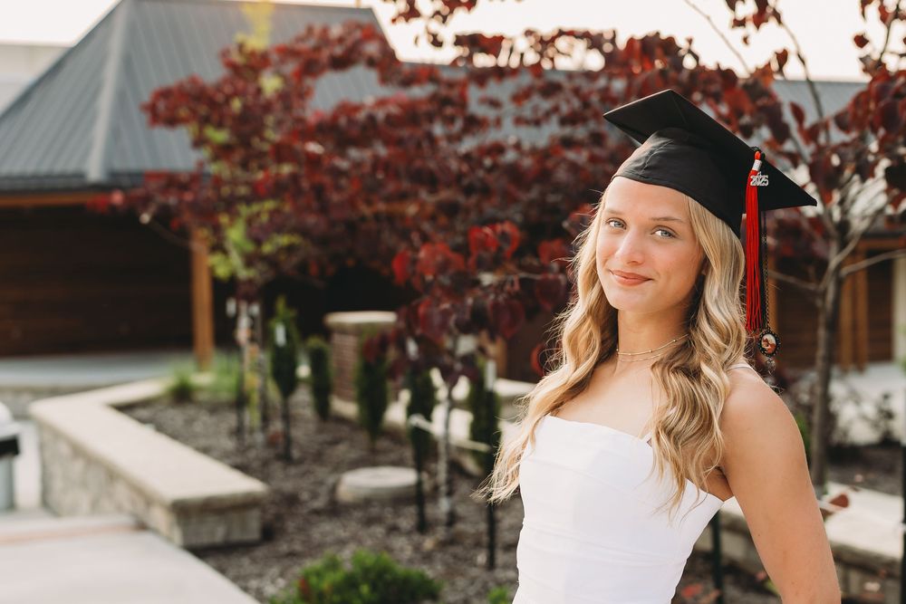 senior graduate girl blonde hair white dress black cap and gown red tassel