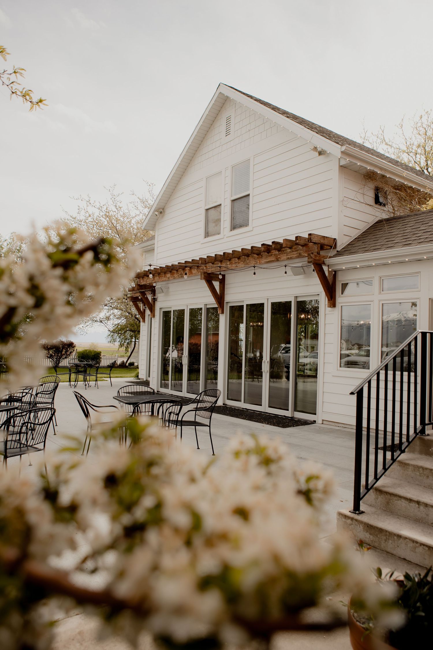 Modern white farmhouse venue with glass doors and outdoor patio seating.