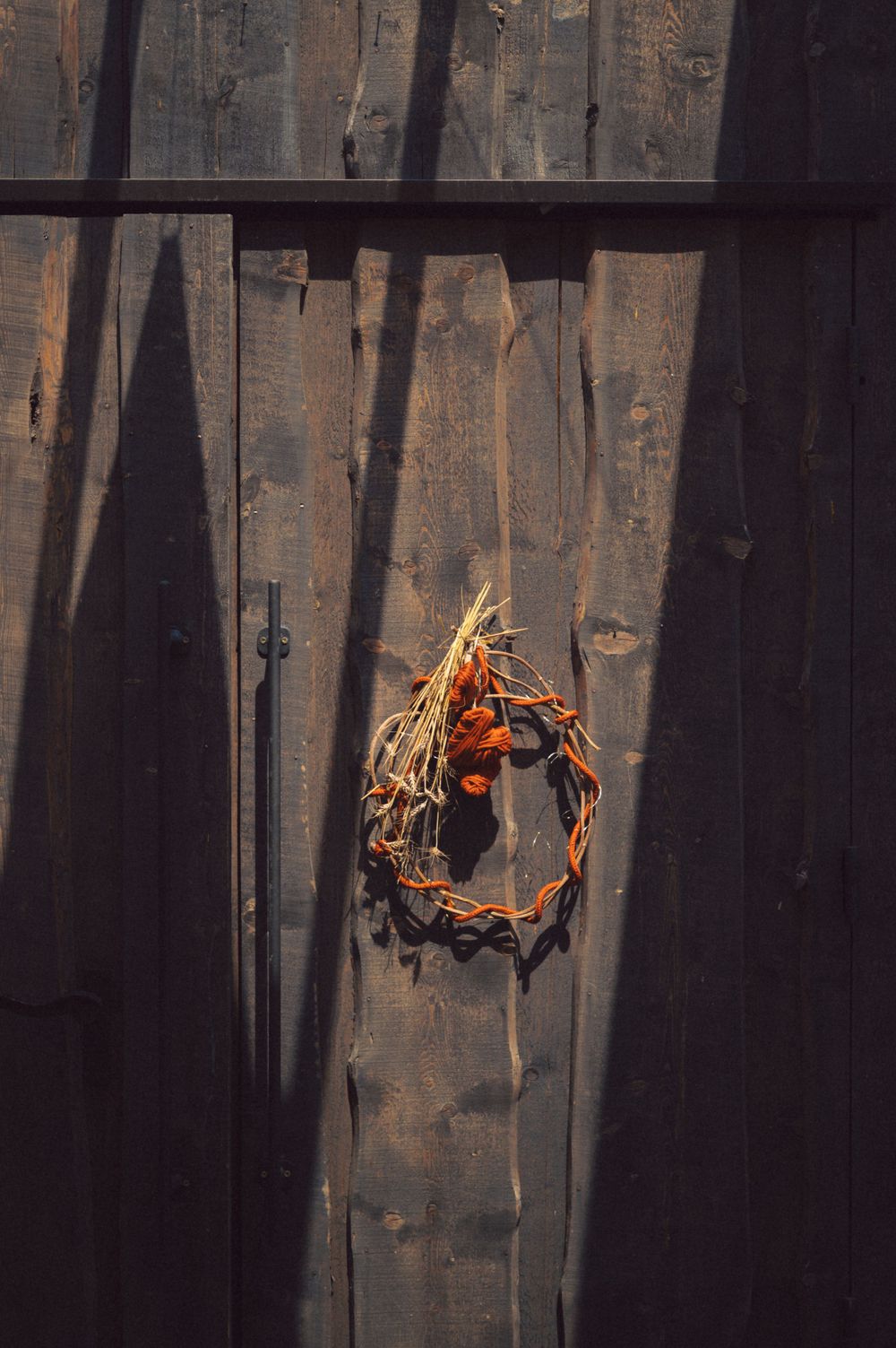 Autumn wreath hanging on dark wooden planks in dramatic lighting.