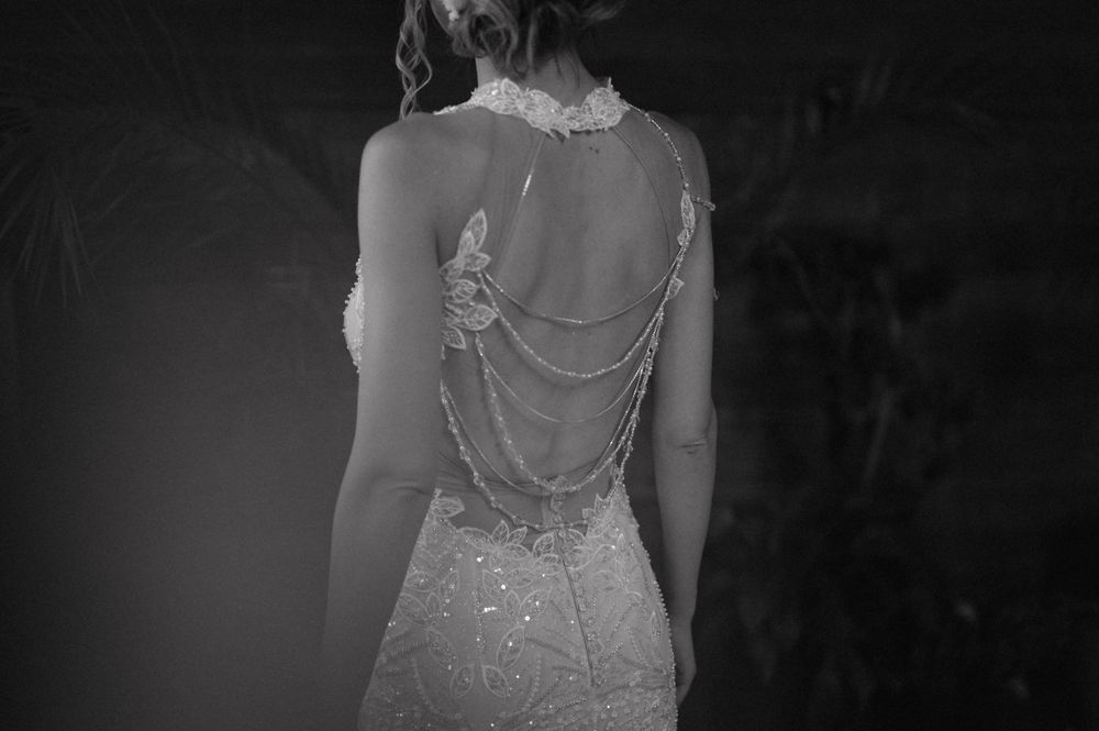 Back view of an intricate wedding dress with delicate beaded chain details.