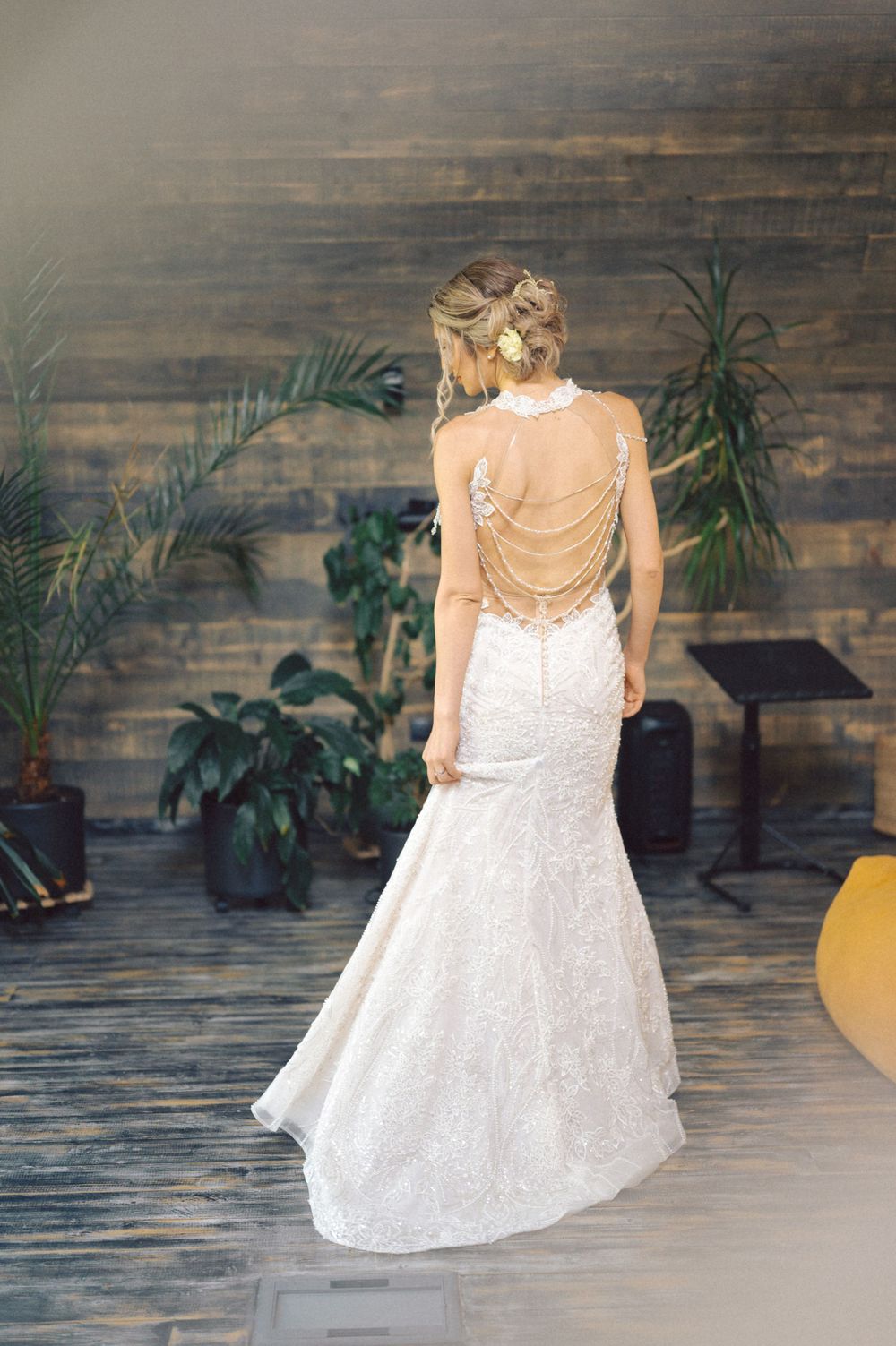 Back view of a mermaid wedding dress with chain details against wooden backdrop.