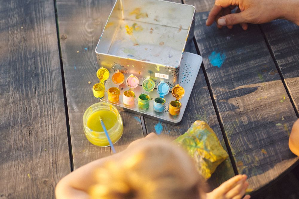 Colorful paint palette and art supplies on wooden table.