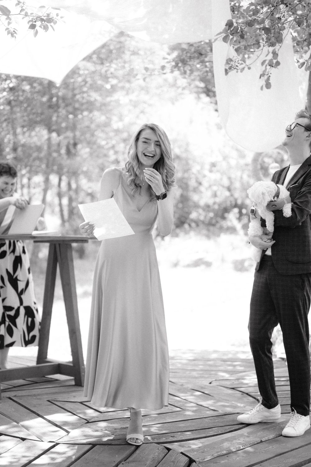 Black and white photo of joyful celebration moment at outdoor wedding ceremony.