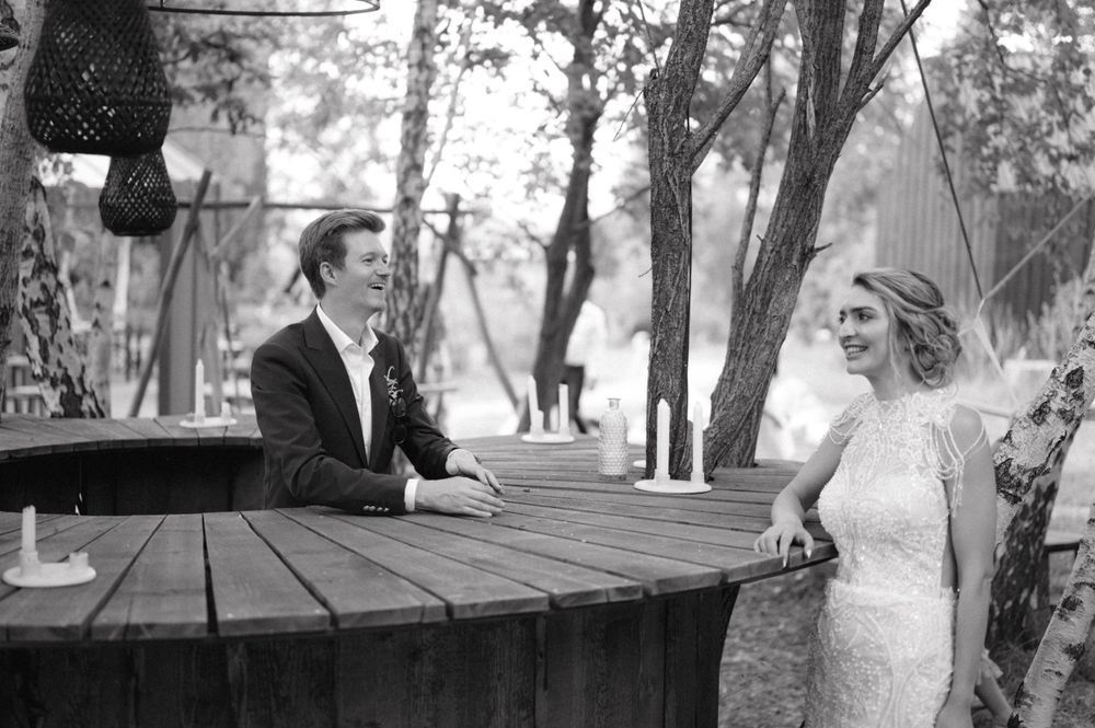 A couple sharing a moment at a rustic wooden table in a garden setting.
