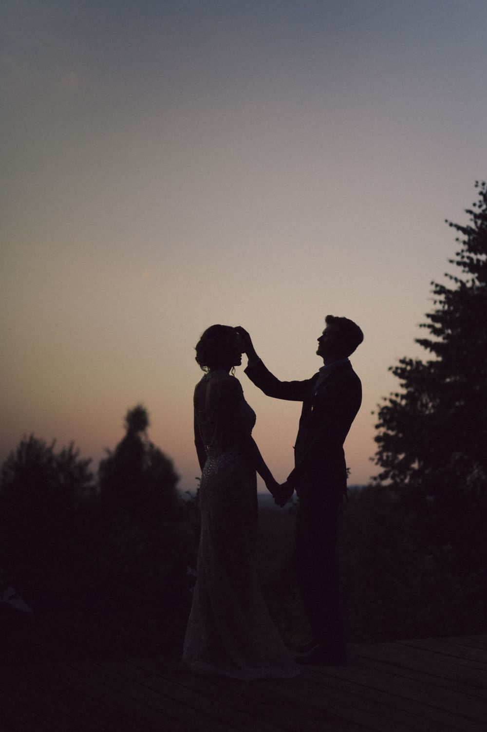A silhouetted couple sharing an intimate moment against a dusky sky.
