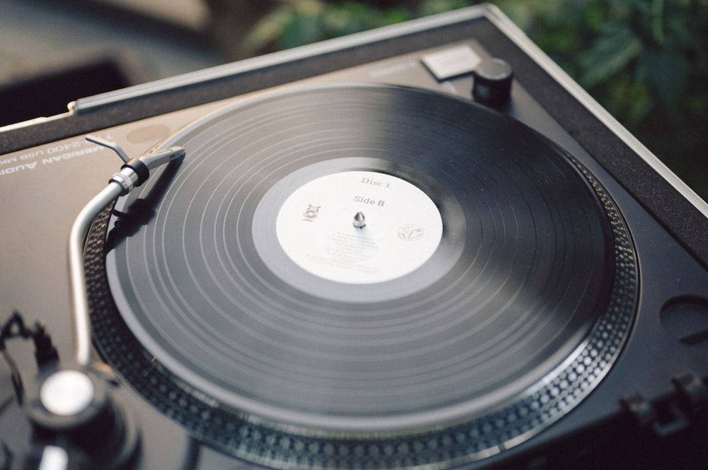 Close-up of a spinning vinyl record on a turntable with detailed tonearm visible.